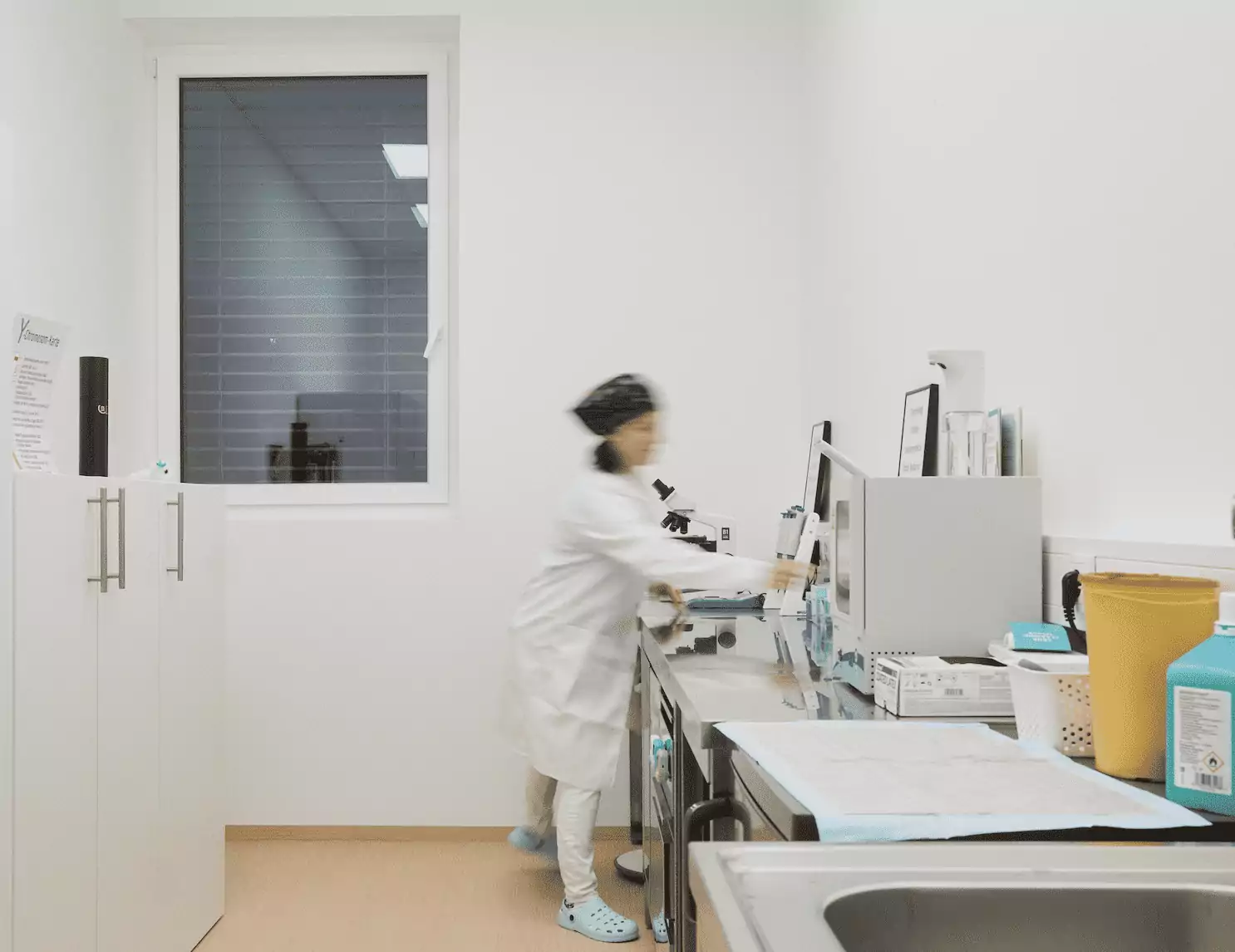 Embryologin im Labor an Mikroskop mit Sicht auf den gesamten Raum